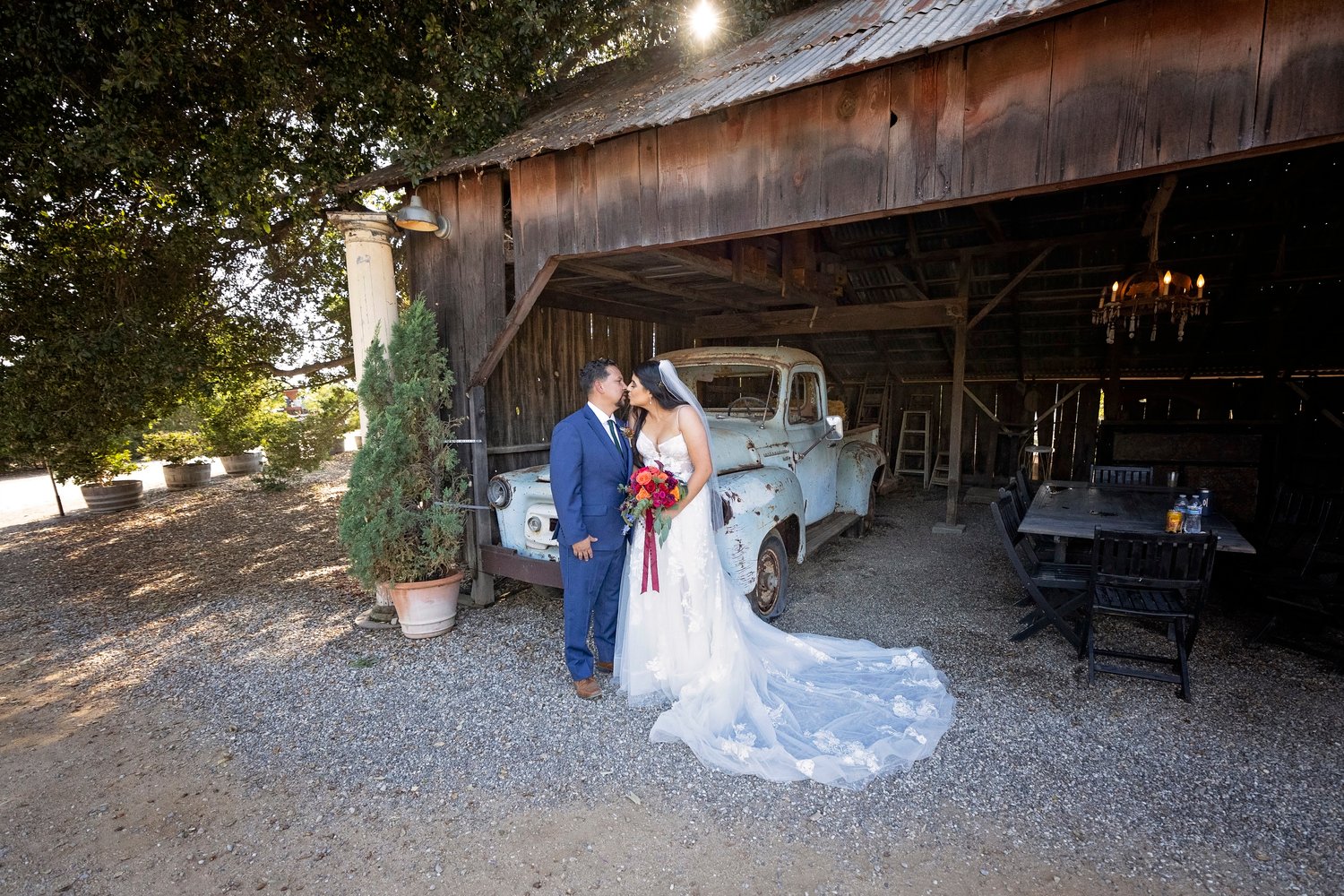bride and groom kissing in front of a vintage truck at the Dana Powers House