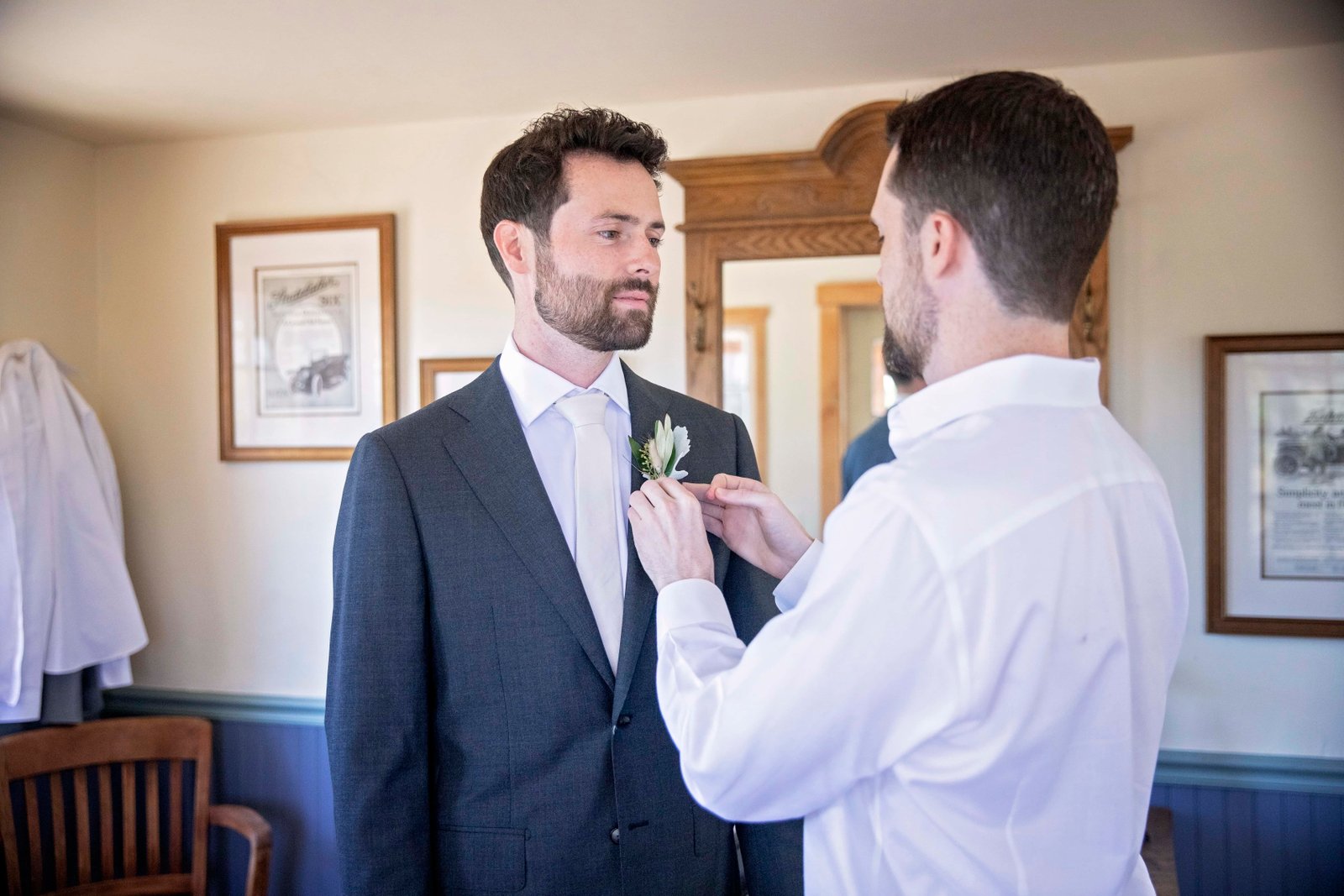 groom getting help with his boutonniere from his twin brother
