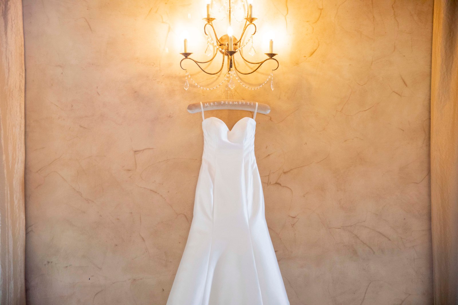 wedding dress hanging from a wall sconce
