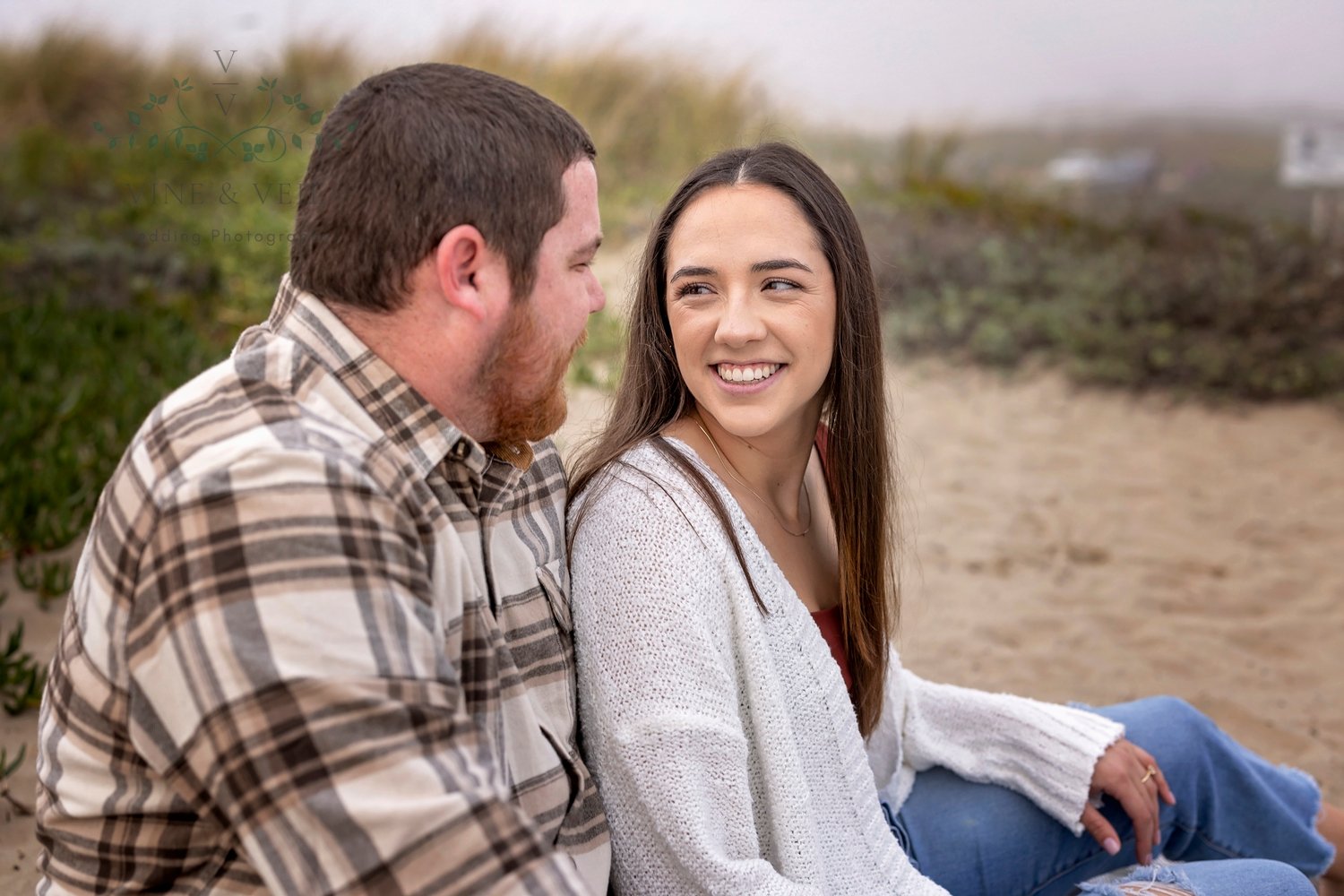 woman looking at her fiance while they are sitting in the sand