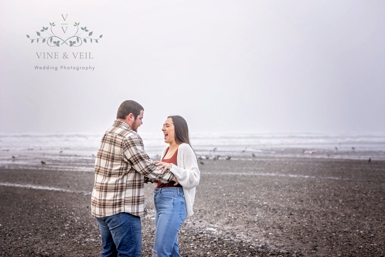 couple playing at the beach during their engagement photoshoot
