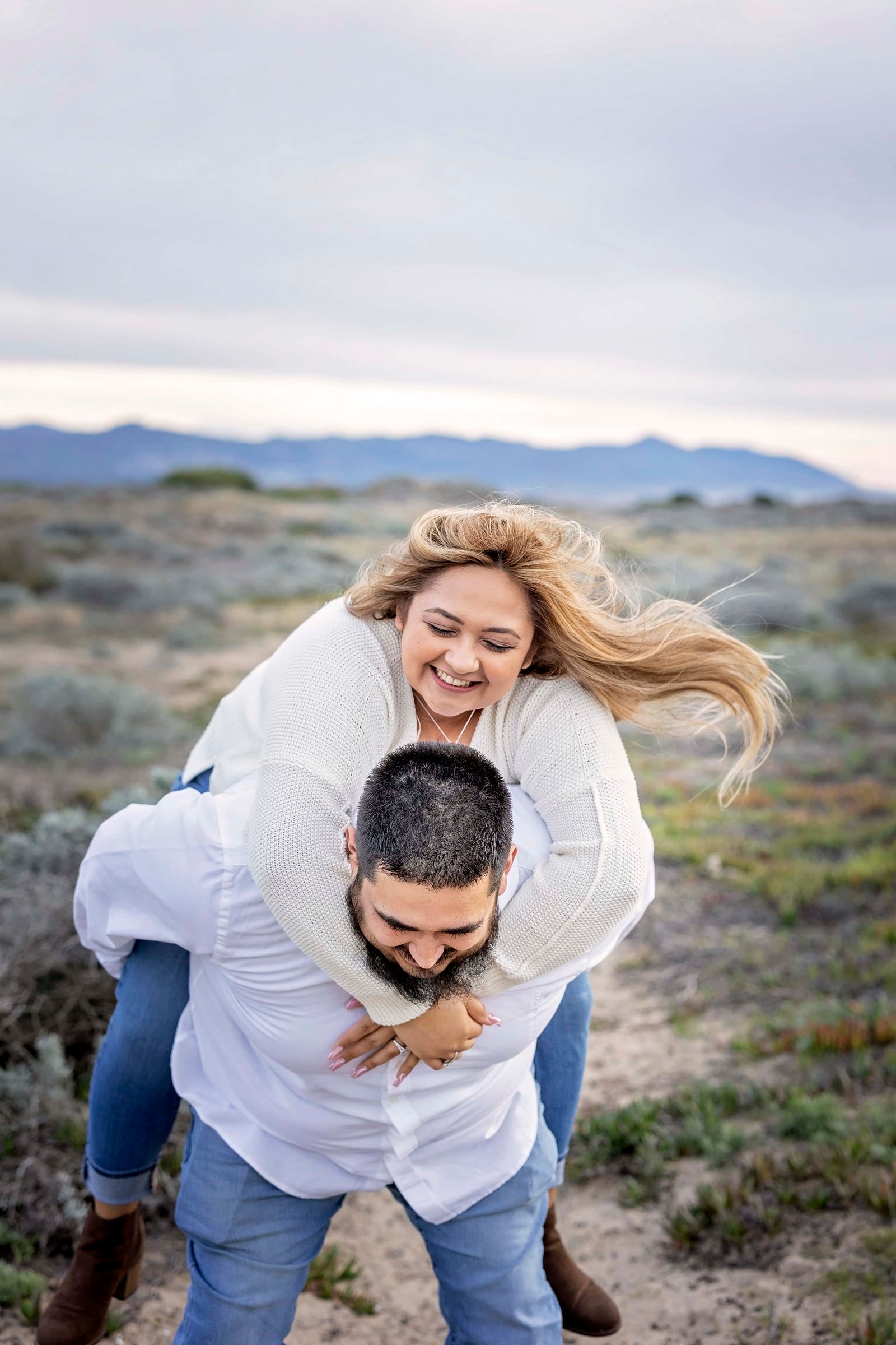 couple giving piggy back rides during their engagement photoshoot
